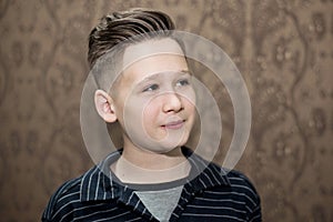 Stylish modern retro haircut side part with mid fade with parting of a school boy guy in a barbershop on a brown background