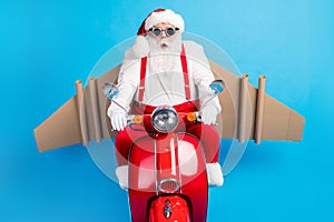 Stylish modern surprised white grey hair bearded santa claus with craft plane drive x-mas christmas red scooter fast