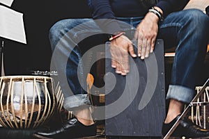 Stylish musician playing the Cajon drums.