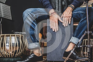 Stylish musician playing the Cajon drums.