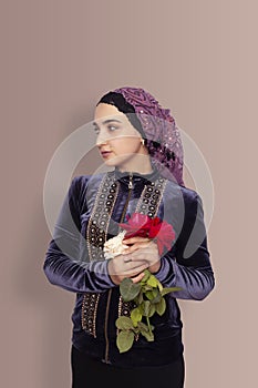 Stylish Muslim woman in traditional Islamic clothing holding flower bouquet. Portrait of a beautiful middle-eastern girl with the