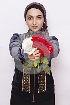 Stylish Muslim woman in traditional Islamic clothing holding flower bouquet. Portrait of a beautiful middle-eastern girl with the