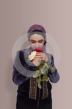 Stylish Muslim woman in traditional Islamic clothing holding flower bouquet. Portrait of a beautiful middle-eastern girl with the