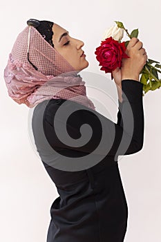 Stylish Muslim woman in traditional Islamic clothing holding flower bouquet. Portrait of beautiful middle-eastern girl in Hijab.