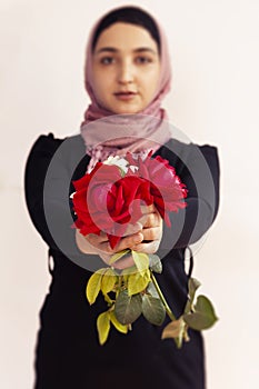 Stylish Muslim woman in traditional Islamic clothing holding flower bouquet. Portrait of beautiful middle-eastern girl in Hijab.