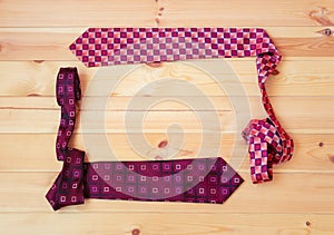 Stylish neckties as a frame on wooden background. Top view