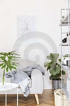 Stylish nordic home interior with creative wooden desk, grey bookstand, accessories, design grey sofa and modern furniture.