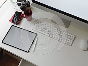 Stylish office desk with blank screen tablet, computer, smartphone, office supplies and copy space