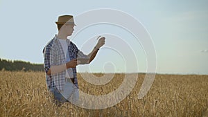 Stylish old caucasian farmer walking in the golden wheat field on his farm during the morning sunrise.