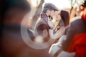Stylish old fashioned couple among crowd looking at each other outdoors in backlight. Man wearing tweed flat cap, brown
