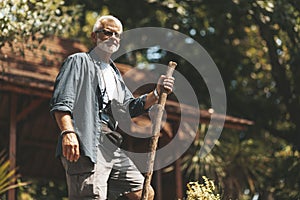 Stylish old man travels with a stick in his hand