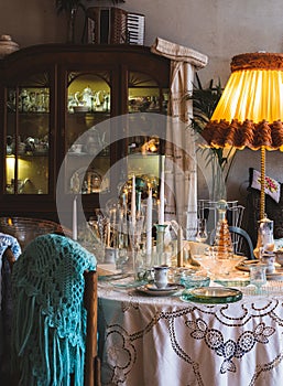 Stylish old vintage interior design. Wooden furniture. Glassware on the table. Retro floor lamp. Knitted shawls.