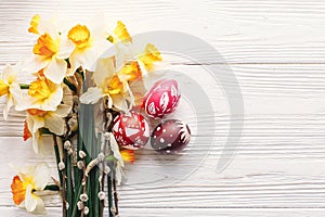 stylish painted easter eggs on rustic wooden background with spring flowers and willow branches. happy easter greeting card flat