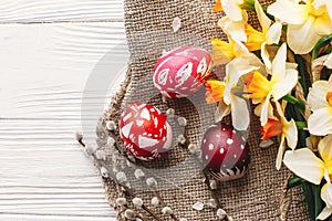 stylish painted easter eggs on rustic wooden background with spring flowers and willow branches. happy easter greeting card flat