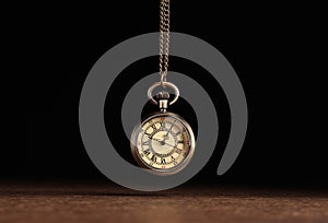 Stylish pendulum above wooden table on black background. Hypnotherapy session