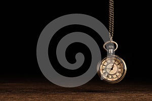 Stylish pendulum above wooden table on black background, space for text. Hypnotherapy session