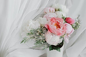 Stylish peonies bouquet on background of soft white fabric, flowers in ceramic vase. Mothers day