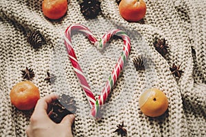 Stylish peppermint candy cane in heart shape and pine cones and