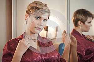 Stylish pin up short hair blonde woman with plus size curvy body posing in fashion red bathrobe near the mirror in the