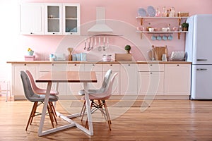 Stylish pink kitchen interior with table and chairs