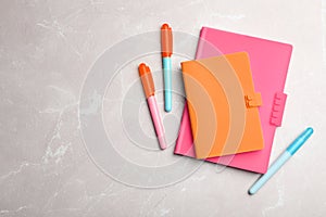 Stylish pink and orange notebooks, pens on table, flat lay. Space for text