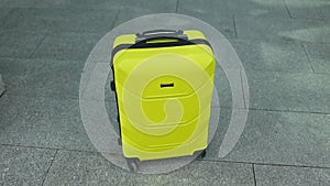 Stylish Plastic luggage suitcase standing at airport, Yellow travel bags waiting in terminal. Transportation and