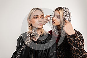 Stylish portrait gorgeous two young women blondes in fashionable elegant clothes with leopard print on background of vintage wall