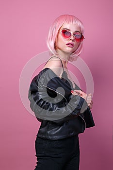 Stylish portrait of woman in sunglasses with bright colored pink hair and pink make-up in sunglasses