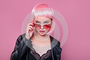 Stylish portrait of woman in sunglasses with bright colored pink hair and pink make-up in sunglasses