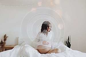 Stylish pregnant mom hugging belly with love and care, waiting for baby. Motherhood concept, magic time. Happy pregnant woman in