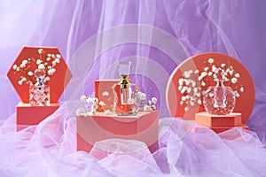 Stylish presentation of perfume bottles and gypsophila flowers on light violet fabric