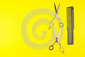 Stylish Professional Barber Scissors and comb on yellow background. Hairdresser salon concept, Hairdressing Set. Haircut