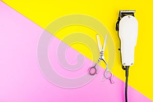 Stylish Professional Barber Scissors and White electric clippers on yellow and pink background. Hairdresser salon concept,