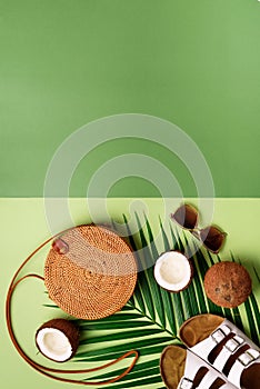 Stylish rattan bag, coconut, birkenstocks, palm branches, sunglasses on olive green background. Banner. Top view with