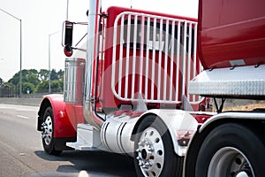 Stylish red big rig semi truck with day cab and safety guard against possible displacement of the load during braking and with re