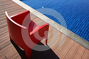 Stylish red chair near the blue pool. Minimalism in design.