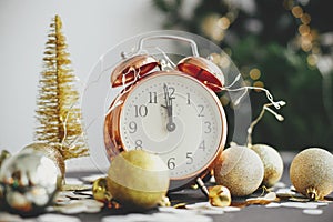 Stylish retro clock, christmas glitter baubles and golden lights on moody background. Happy New Year! New year party concept.