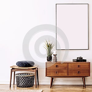 Stylish and retro living room with design vintage wooden commode, chair, footrest, black lamp and elegant personal accessories.