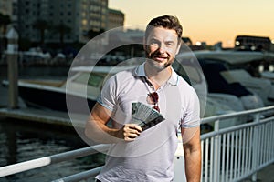 Stylish Rich man hold dollars. Handsome Rich man outdoors portrait. Portrait of stylish Rich male model outdoor. Fashion