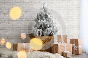 Stylish room interior with beautiful Christmas tree and gifts near white brick wall