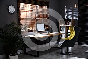 Stylish room interior with modern computer and comfortable office chair