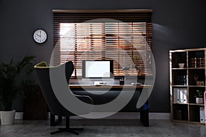 Stylish room interior with modern computer and comfortable office chair