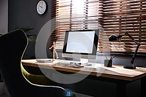 Stylish room interior with modern computer and comfortable office chair