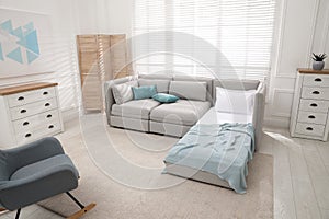 Stylish room interior with sleeper sofa and rocking chair. Additional place for guest