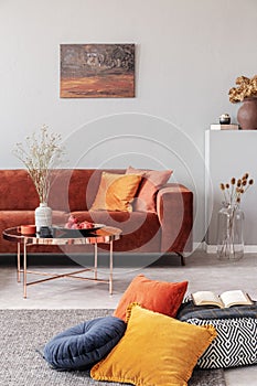 Stylish round coffee table with flowers in the middles of beautiful living room interior