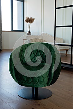 Stylish round green velvet armchair in a modern interior. Soft selective focus