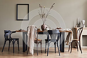 Stylish rustic interior of dining room with walnut wooden table, retro chairs, decoration, fireplace, dried flower, candlestick.