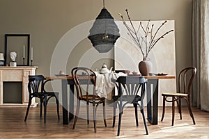 Stylish rustic interior of dining room with walnut wooden table, retro chairs, decoration, fireplace, dried flower, candlestick.