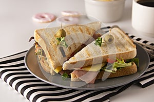 Stylish sandwich. Toasted double panini with ham, cheese fresh vegetables. Snack at work or lunch. Light background