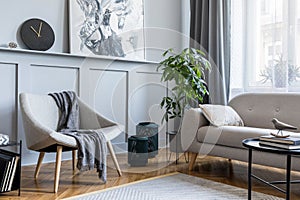 Stylish scandinavian home interior of living room with design gray sofa, armchair and personal accessories. photo